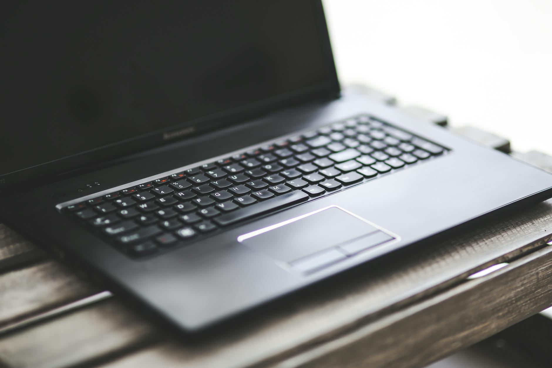 Best Cheap WordPress Hosting for Beginners in 2026 - Sleek black laptop resting on a rustic wooden table. Ideal for workspace